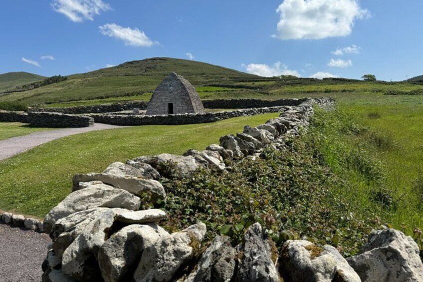 A stone wall, a stone building, and a grassy field with hills in the background. 5
