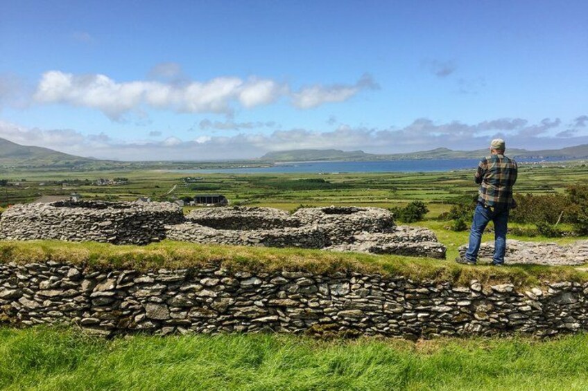 A stone wall, a person, and a landscape with hills and a body of water. 2