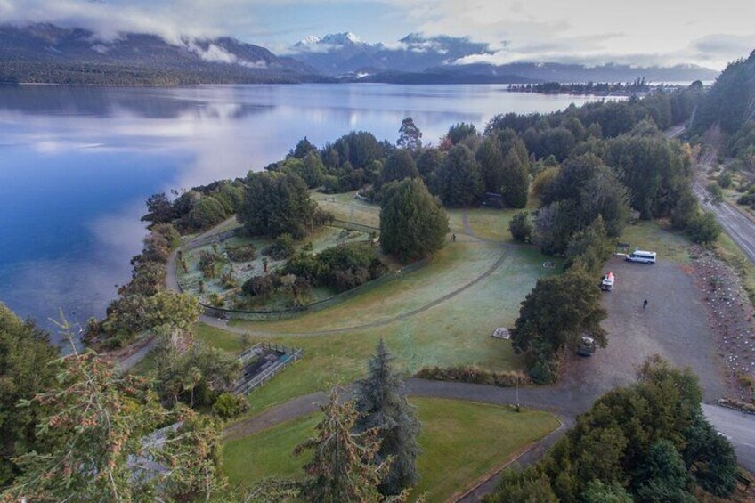 A lake surrounded by trees and a road with vehicles. 4