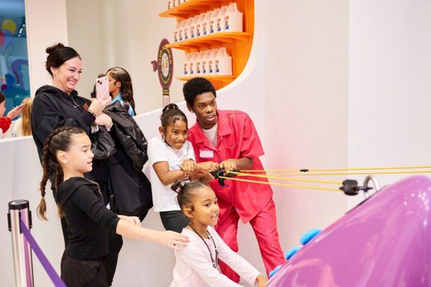 A group of people engaged in a hands-on activity, possibly a science experiment or educational demonstration, with various equipment and a purple object in the foreground. 3