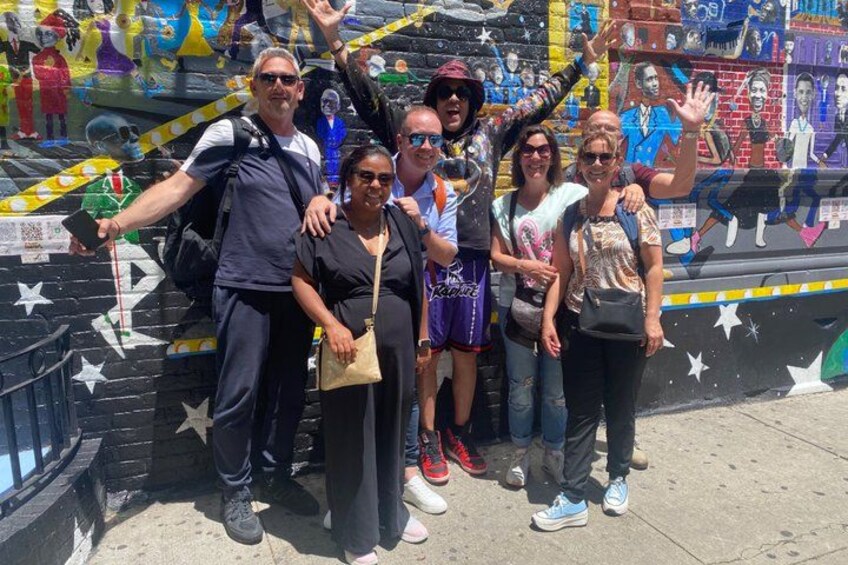 A group of people posing in front of a colorful mural with stars and abstract designs. 1