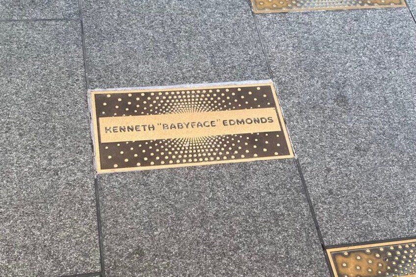 A manhole cover with the name 'Kenneth 'Babyface' Edmonds' engraved on it. 5