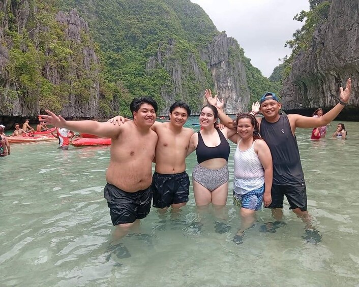 A group of people standing in shallow water with a mountainous landscape in the background. 3