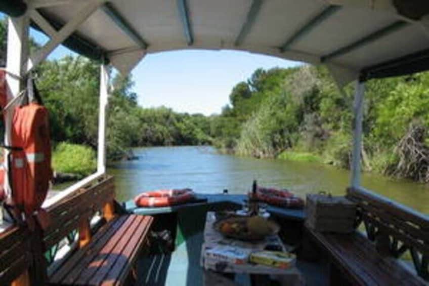 A covered boat with benches and life jackets, surrounded by greenery and a calm river. 5