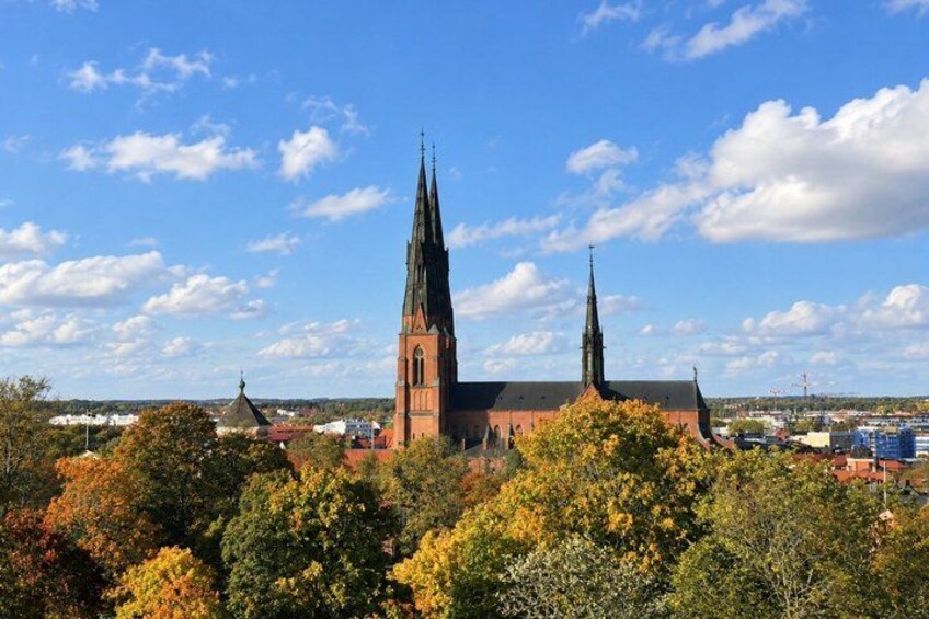 A church with two spires, surrounded by autumn foliage and a clear sky. 2