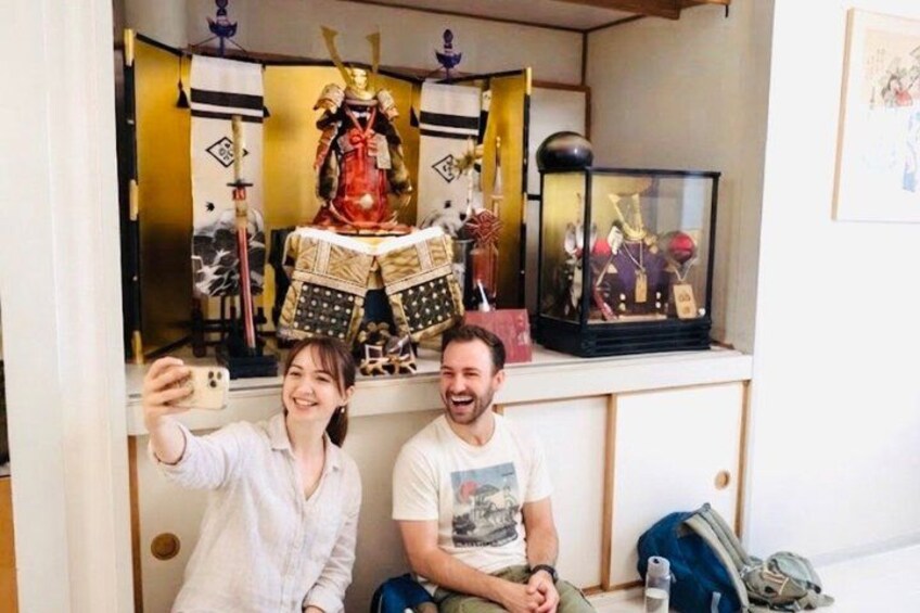 A person taking a selfie with a decorative samurai armor in the background. 1