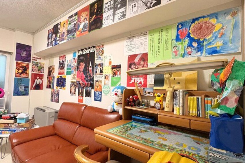 A room with a brown leather chair, a desk with a globe, and walls covered with posters and drawings. 2