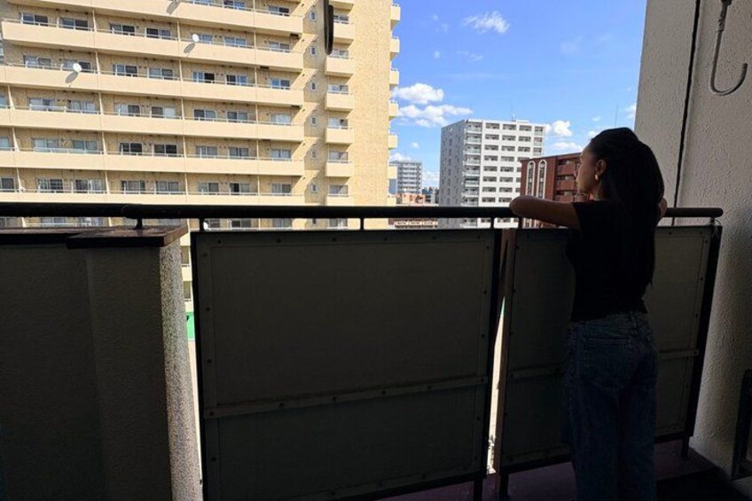 A person standing on a balcony overlooking a cityscape with tall buildings. 3