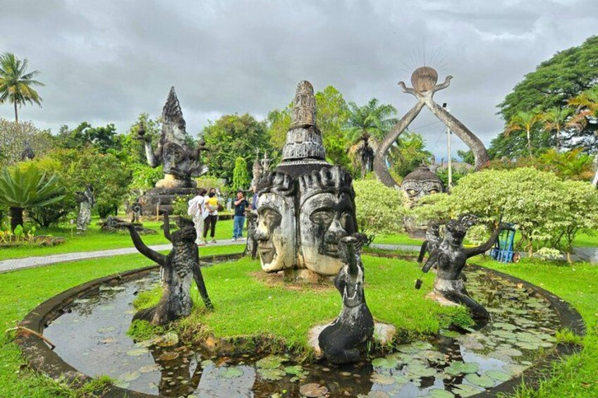 A garden with statues, a pond, and a large central sculpture. 3