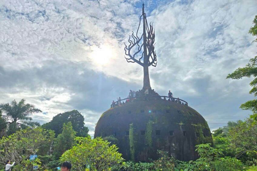 A large tree sculpture on a dome-shaped structure surrounded by lush greenery. 2