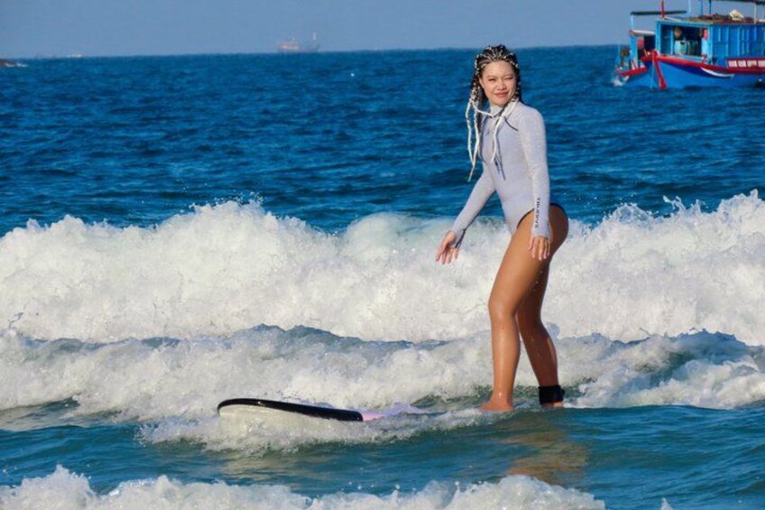 A person surfing on a wave with a boat in the background. 1