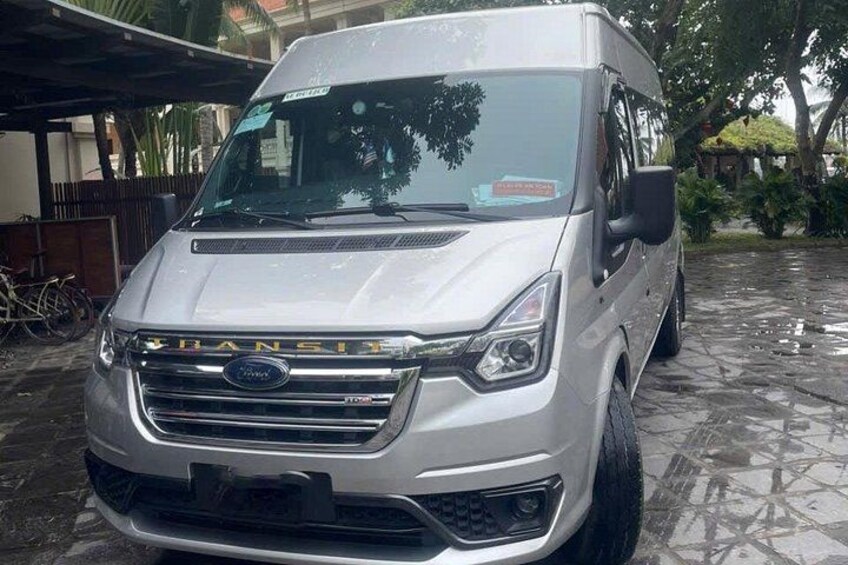 A silver Ford Transit van parked on a wet stone surface. 2