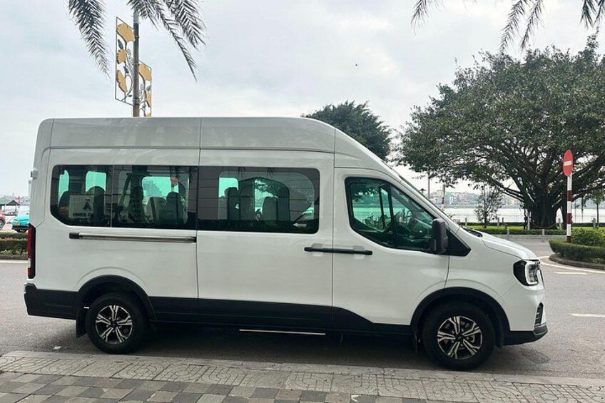 A white van parked on a paved area with palm trees and a stop sign in the background. 3