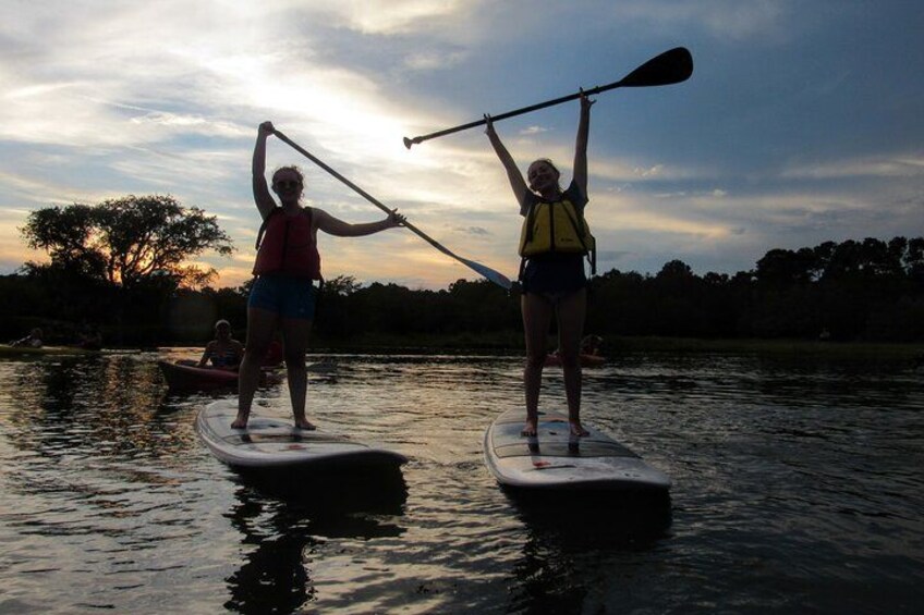 Two people paddleboarding on a calm river at sunset. 4