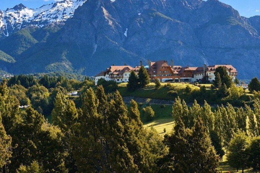 A mountain lodge with a red roof, surrounded by trees and snow-capped mountains. 5