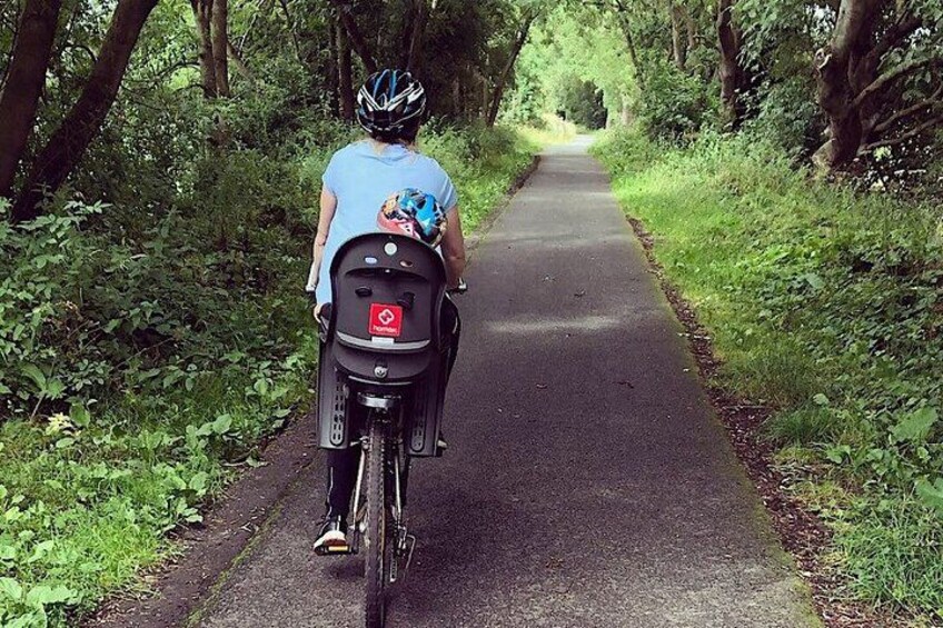 A person riding a bicycle on a paved path surrounded by trees. 3