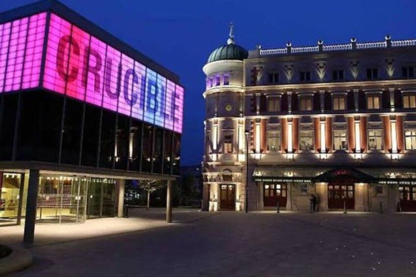 A building with a large illuminated sign reading 'CRUCIBLE' and a classical architectural structure with columns and a dome in the background. 4
