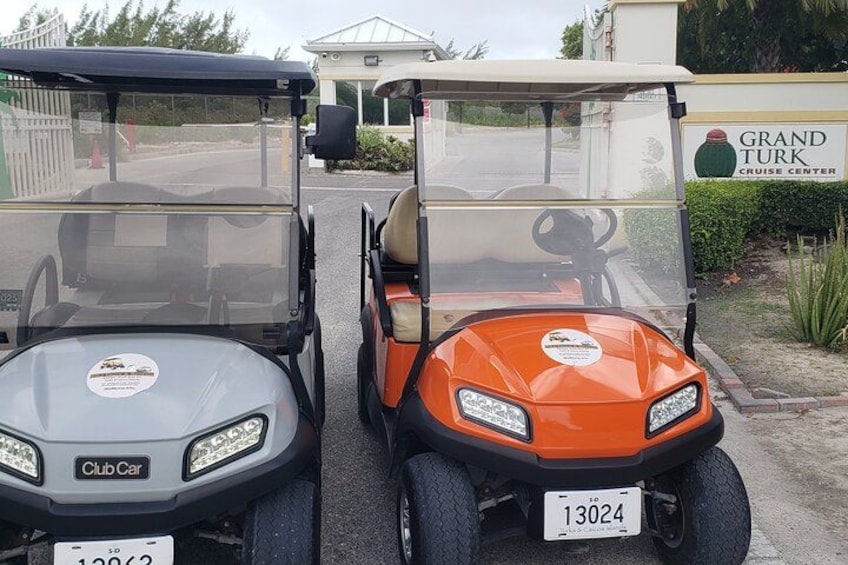 Two golf carts parked in front of a building with a sign that reads 'Grand Turk Cruise Center.' 1