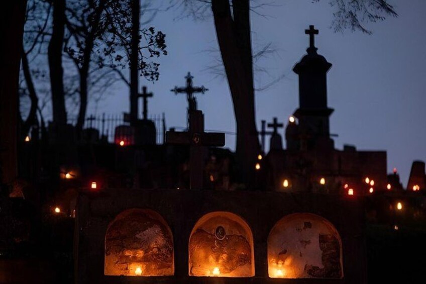 A cemetery at dusk with illuminated tombstones and crosses. 4
