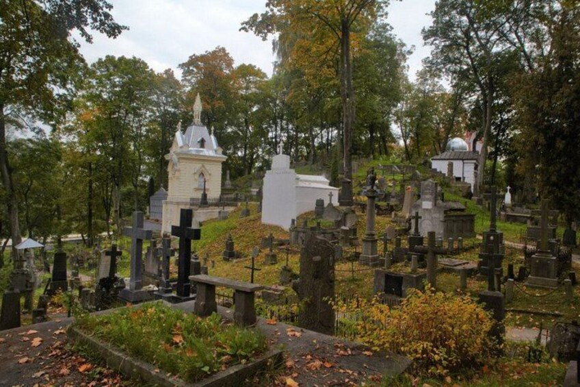 A cemetery with numerous gravestones, a small white church, and a bell tower. 3