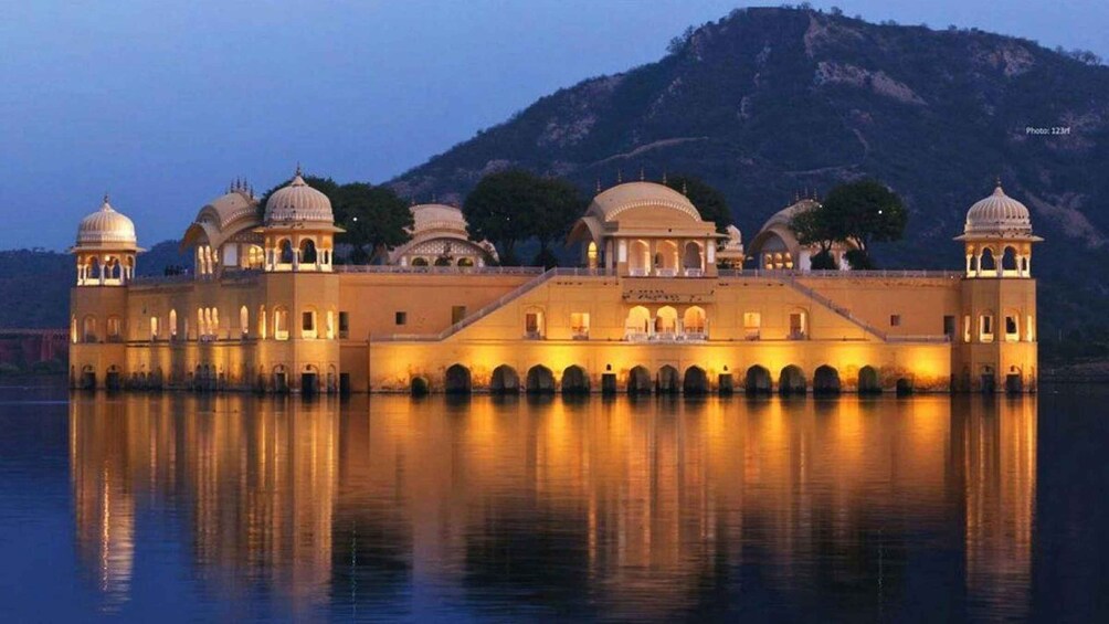 Un palacio con cúpulas y arcos múltiples, reflejado en aguas tranquilas, con una montaña al fondo. 5
