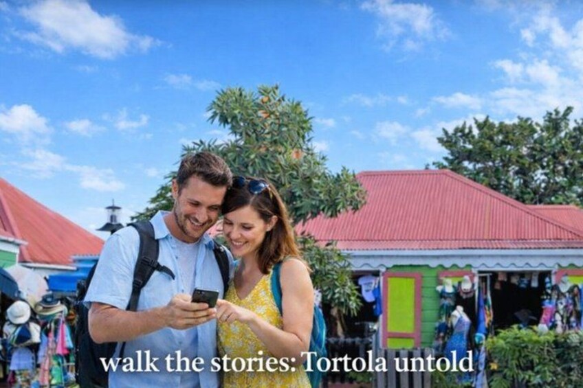 A couple walking in a market with colorful buildings and a clear sky. 1