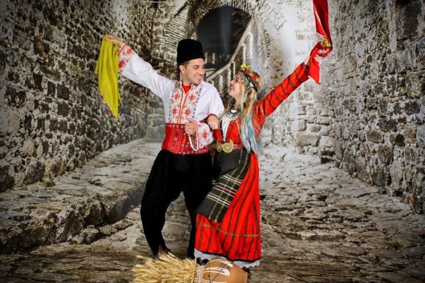 A couple in traditional attire dancing in a stone-walled alley. 5