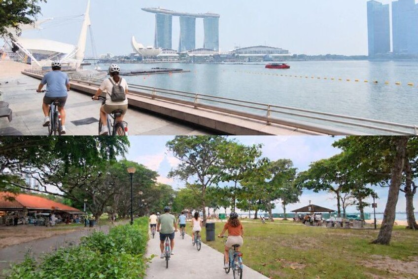 Cyclists on a bridge and a path with trees and a view of a city skyline. 1