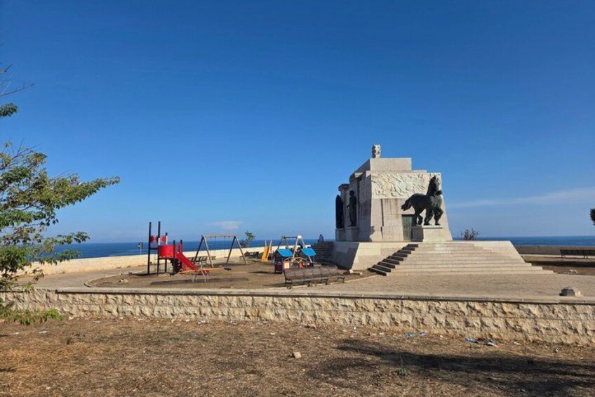 A playground with swings and a slide, a statue of a horse, and a clear blue sky. 2