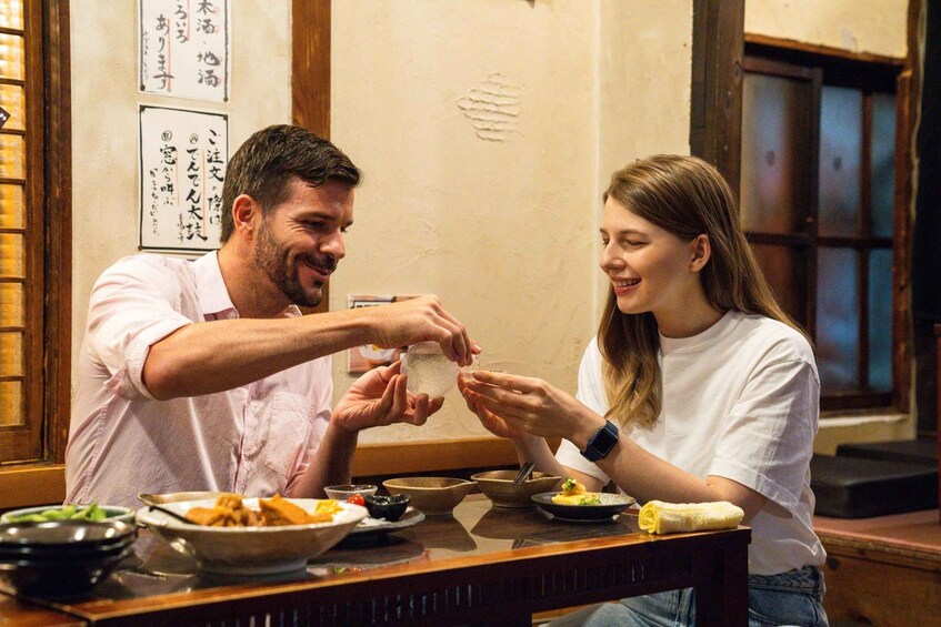 Un hombre y una mujer sentados en una mesa con varios platos, incluyendo un tazón de sopa y un plato de comida. 1