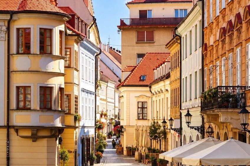 A narrow street lined with historic buildings, some with balconies and awnings. 4
