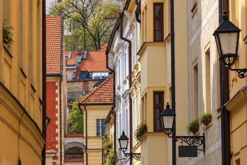 A narrow street with buildings, a red-tiled roof, and black street lamps. 5