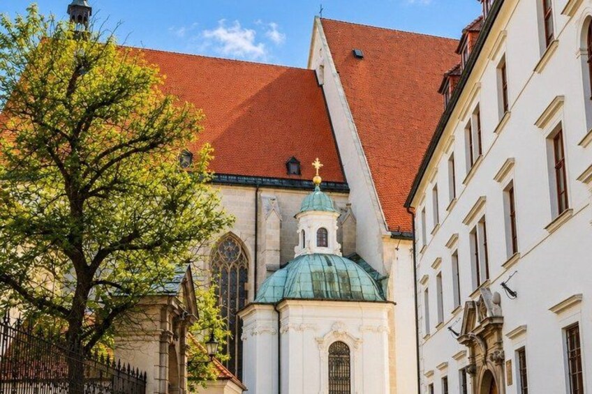 A church with a red roof and a green dome, surrounded by buildings. 3