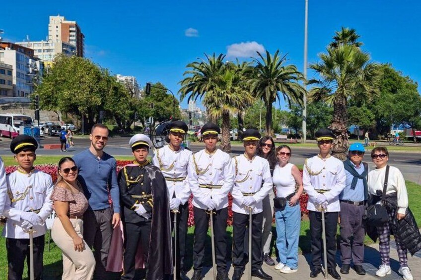 A group of people in uniform standing outdoors with palm trees and buildings in the background. 5