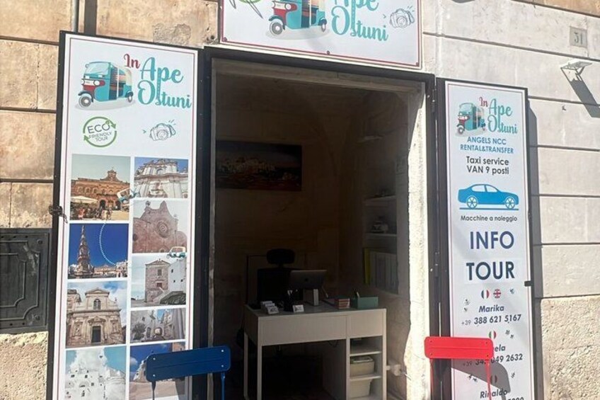 A travel agency named 'In Ape Oluni' with a signboard displaying various travel-related images and contact information. 2