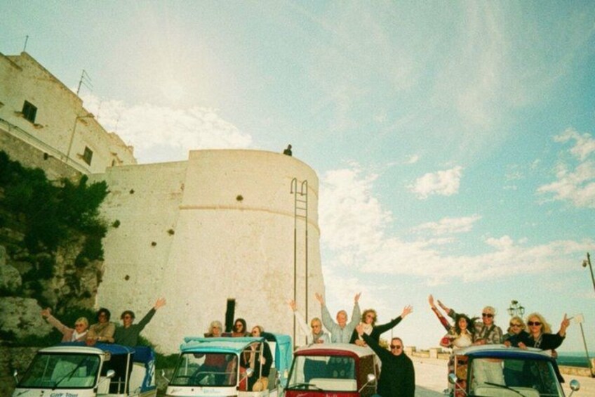 A group of people celebrating in front of a historic fort with a clear sky. 4
