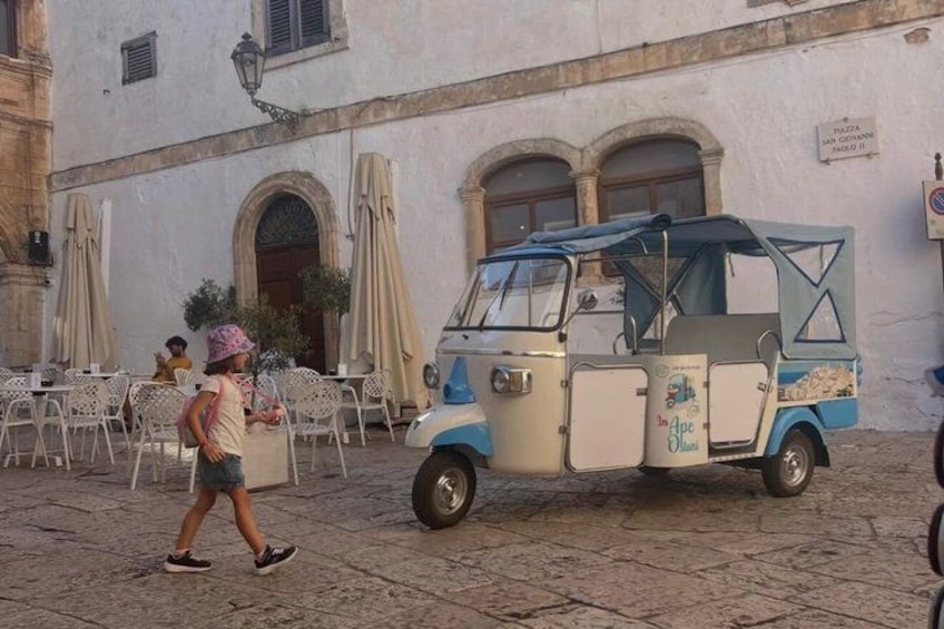 A vintage ice cream cart parked in front of a building with outdoor seating. 5