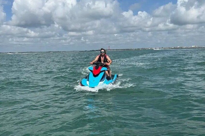 A person riding a jet ski on a body of water with a cloudy sky in the background. 4