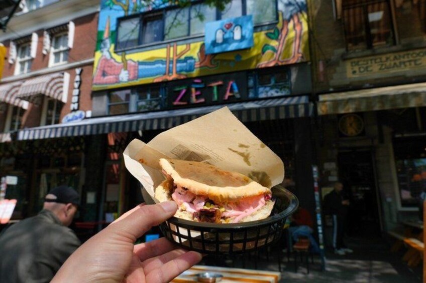 A hand holding a basket with a sandwich. 3