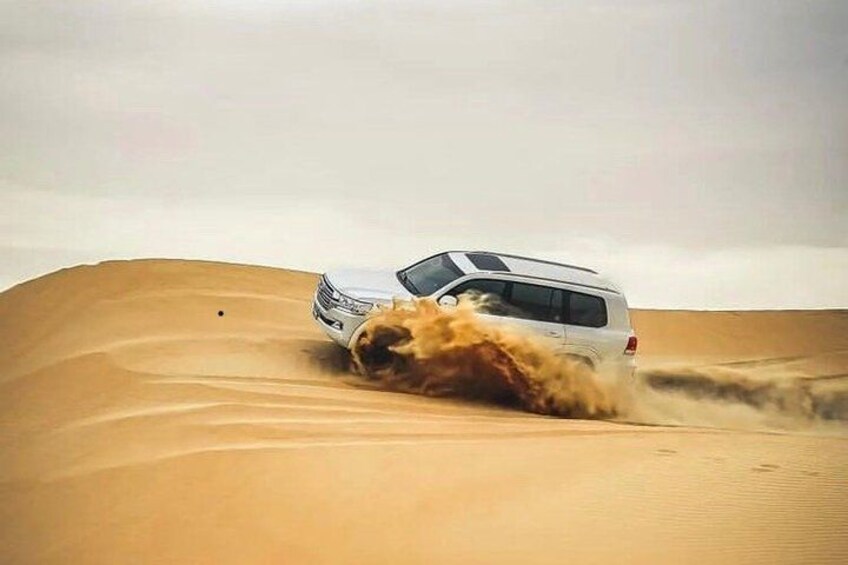 A vehicle driving through a desert with sand dunes. 4