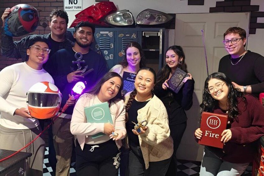 A group of people holding various items, including a helmet, a book, and a red card with a logo. 1