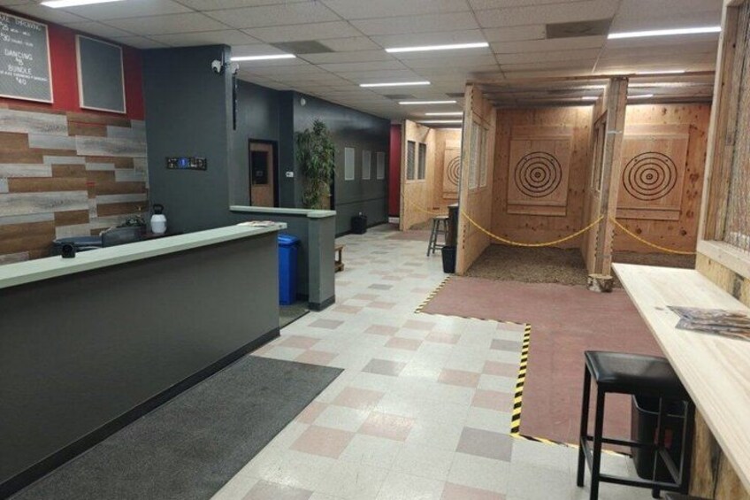 An indoor shooting range with wooden shooting booths, a counter, and a check-in area. 2