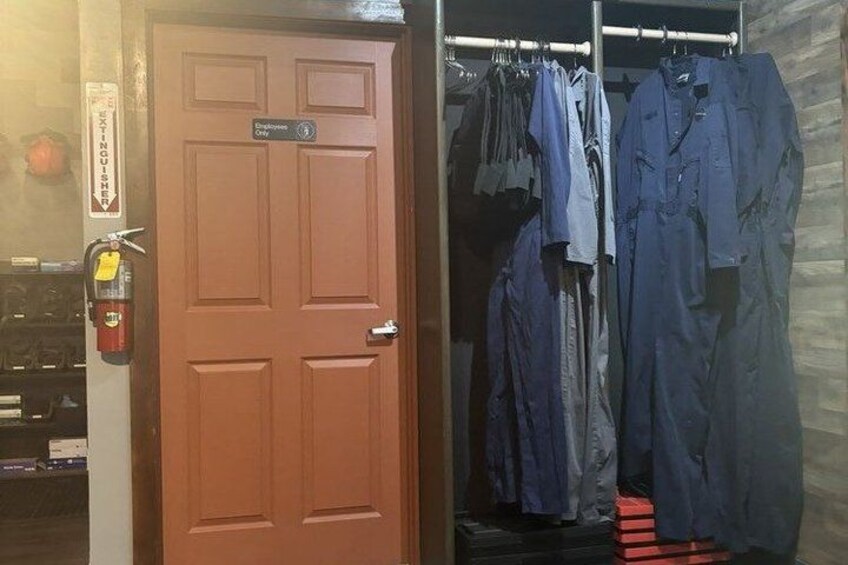 A wooden door with a fire extinguisher and a sign, a closet with hanging clothes, and a fire hose on the floor. 4