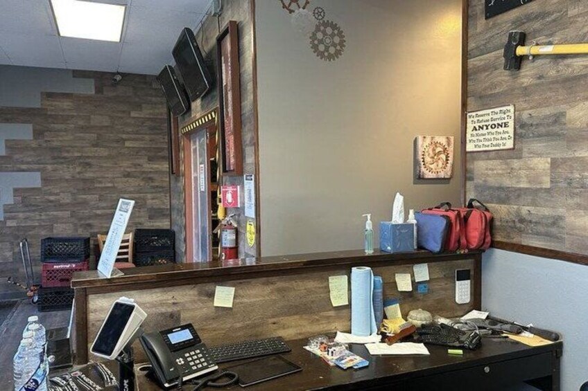 A reception desk with a phone, keyboard, and various papers. There are sticky notes on the wall and a fire extinguisher on the left. 5