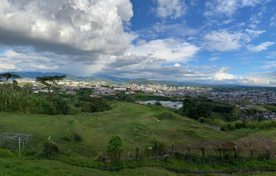 A cityscape with a green hill in the foreground and a cloudy sky. 3