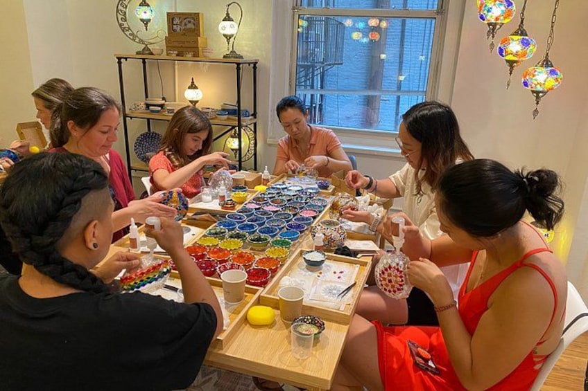 A group of people engaged in a craft activity around a table with colorful materials. 4