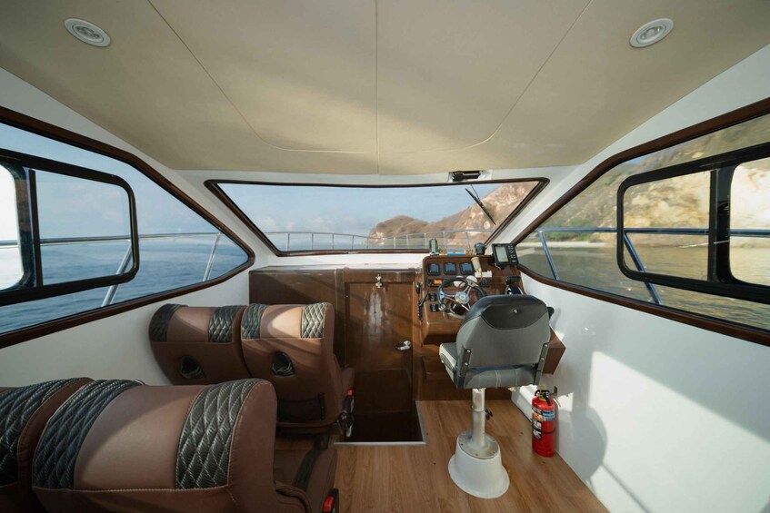 L'intérieur d'un bateau, avec deux sièges rembourrés, un volant et un panneau de commande. 3