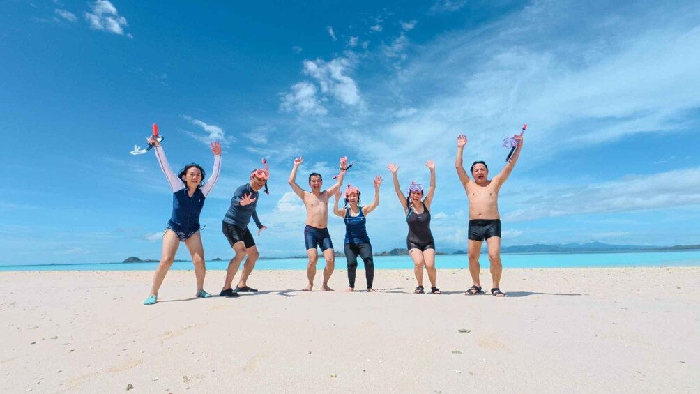 Un groupe de personnes sur une plage, avec un ciel dégagé et une mer calme en arrière-plan. 4