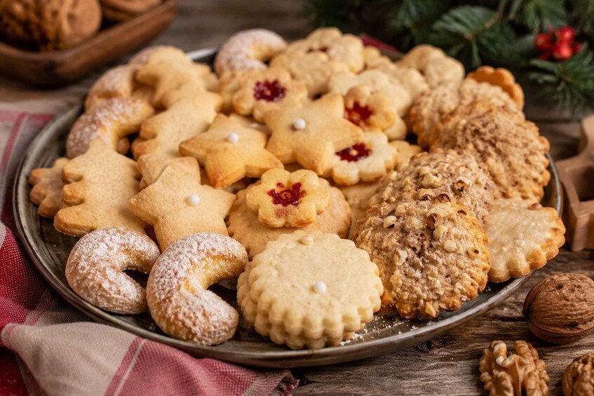 A variety of cookies on a plate, including some with nuts and powdered sugar. 1