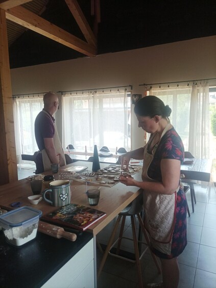 A person preparing food at a wooden table in a kitchen with a window and curtains. 4